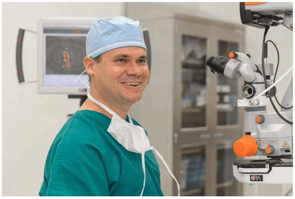 Dr. Stephen M. Tate Smiling in front of Cataract Surgery Microscope